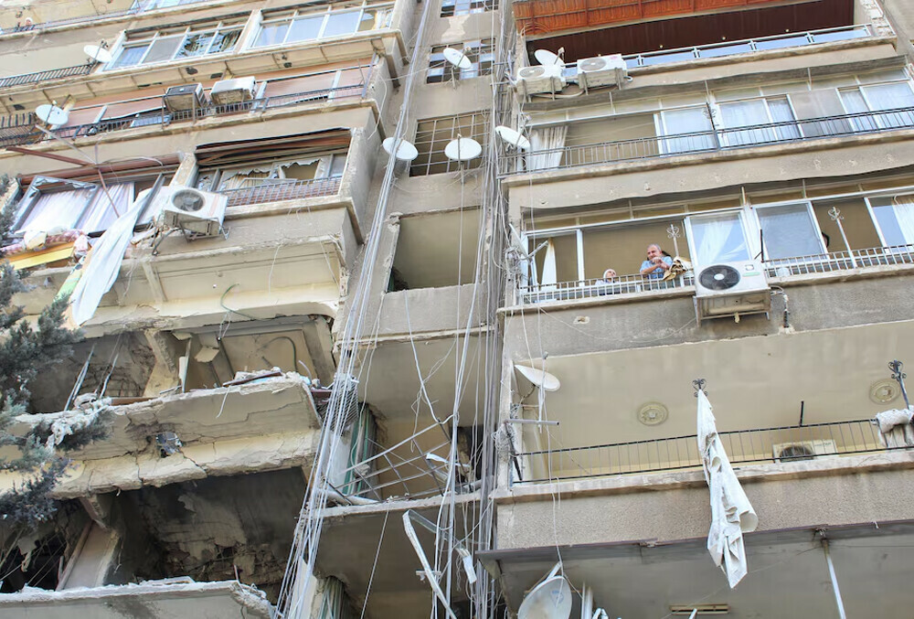  People stand on a balcony of a damaged building in the aftermath of what Syrian state media reported was an Israeli strike in the Mezzah suburb west of Damascus, Syria October 9, 2024. Photo: Reuters 