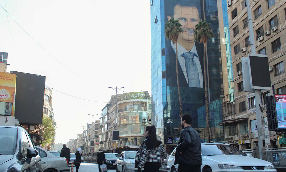  People walk near a poster depicting Syria’s President Bashar al-Assad in Damascus, after last week’s rebel seizure of Aleppo marked the biggest offensive for years, Syria December. Photo: Reuters 