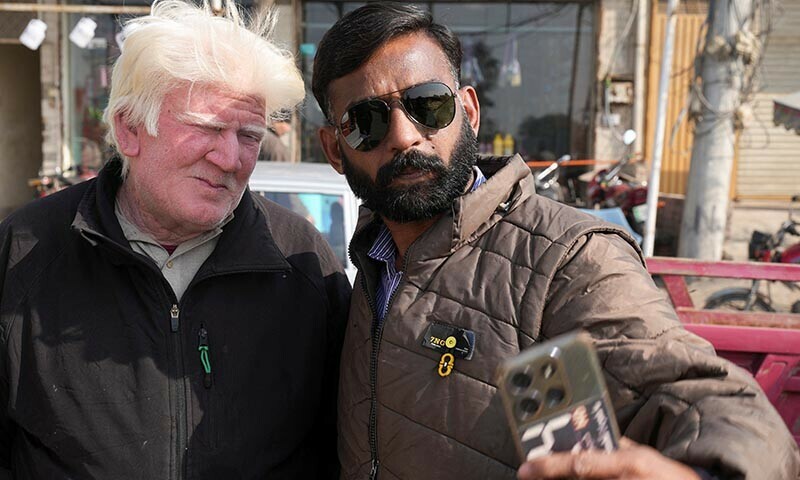 Saleem Bagga, seen by some as a lookalike of US President-elect Donald Trump, poses for a selfie with a customer while selling kheer, along a road in Sahiwal, Pakistan January 13, 2025. — Reuters