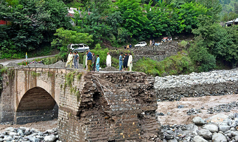 Onlookers gather near a destroyed bridge after flash floods on the outskirts of Muzaffarabad, Azad Jammu and Kashmir, on August 15. — AFP