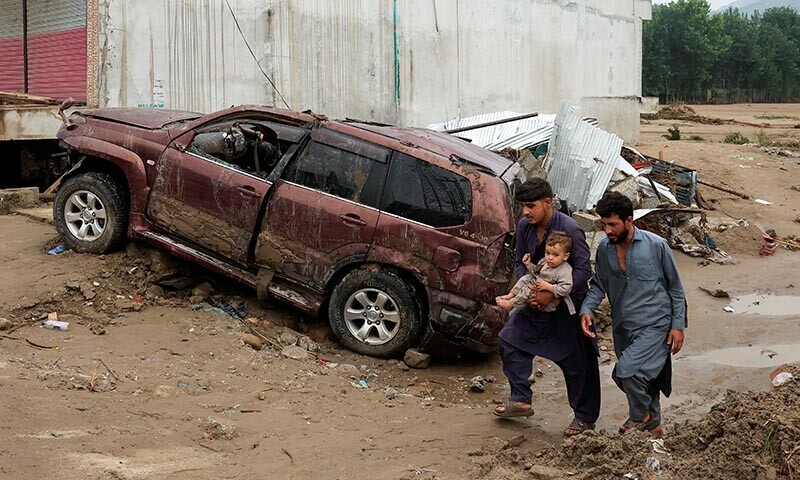 Residents walk past a damaged vehicle following a storm that caused heavy rains and flooding, in Bayshonai Kalay, Buner district, Khyber Pakhtunkhwa on August 17, 2025. — Reuters