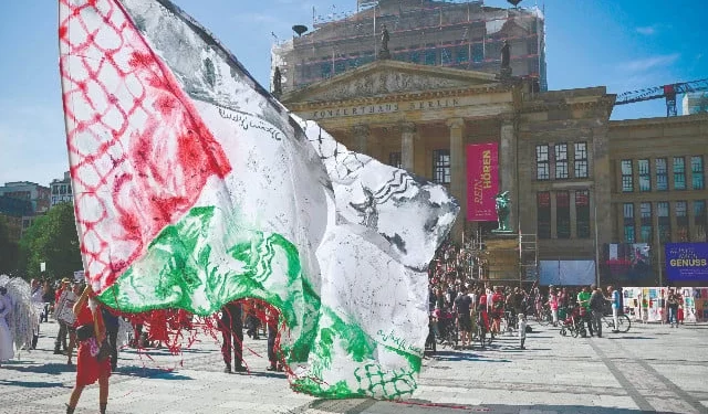 a demonstrator waves a giant palestinian flag as spectators gather for a classical concert at the gendarmenmarkt square outside the konzerthaus concert hall in berlin the concert was performed on world children s day on september 20 for the children of gaza photo afp